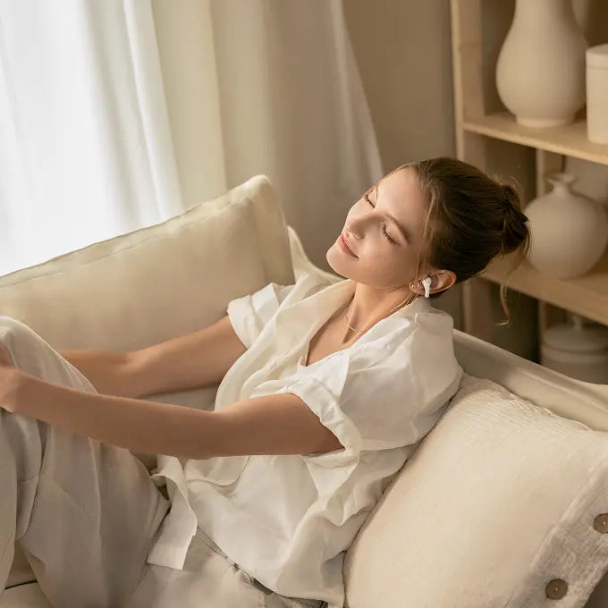 Woman wearing Shokz OpenDots 2 while relaxing at home