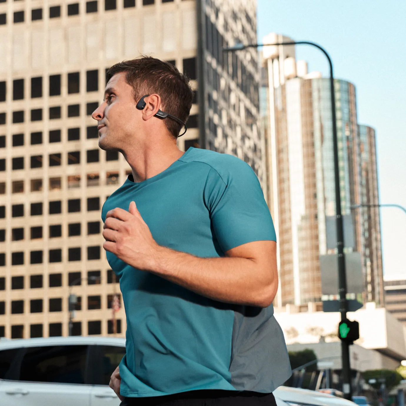 Runner wearing Shokz OpenRun Pro 2 on a city street